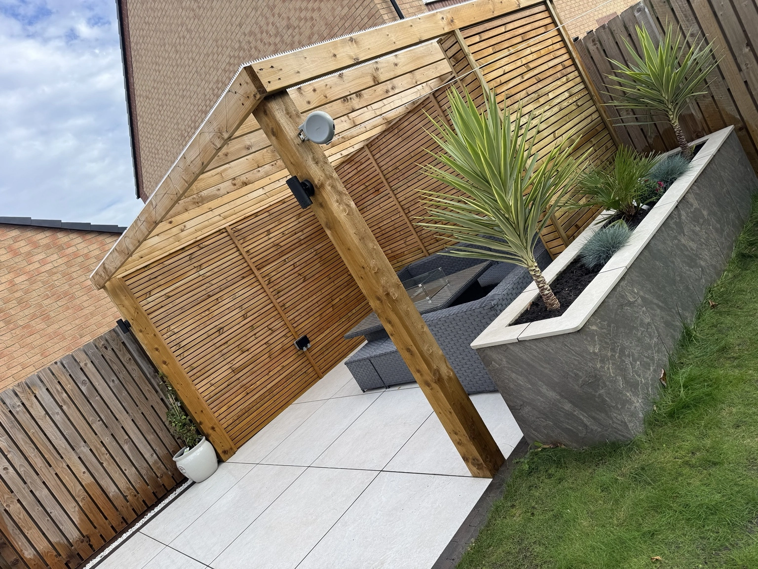 Finished outdoor-living garden with porcelain paving, timber pergola and raised planters